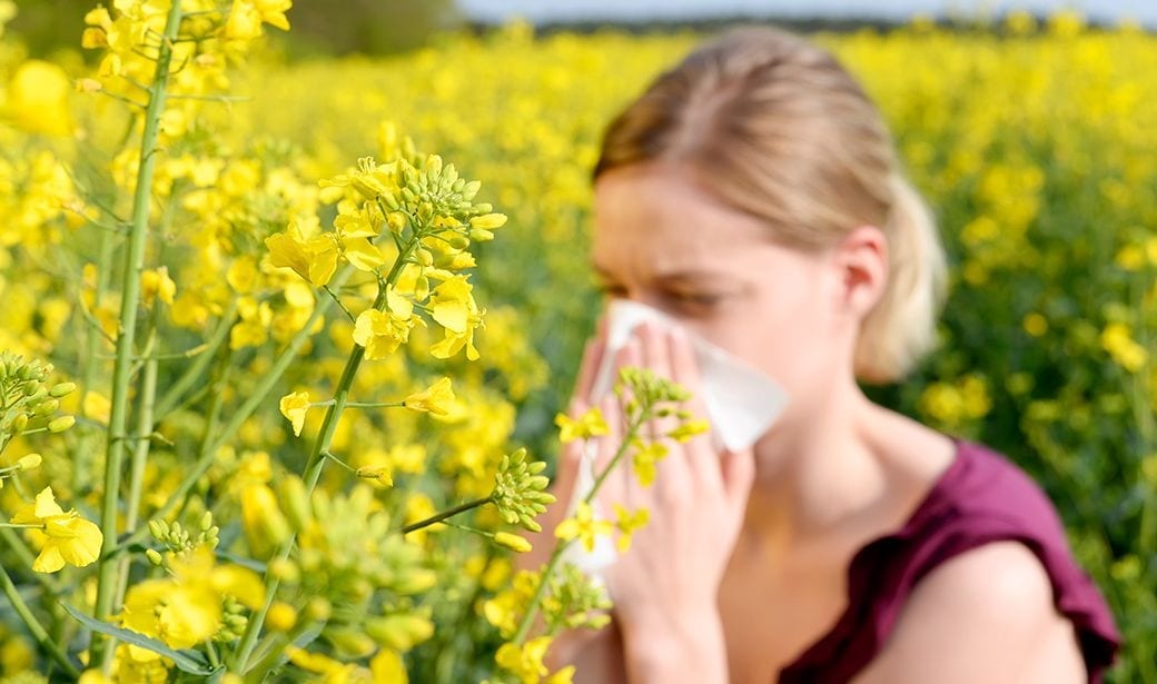 Woman blowing nose in flower field