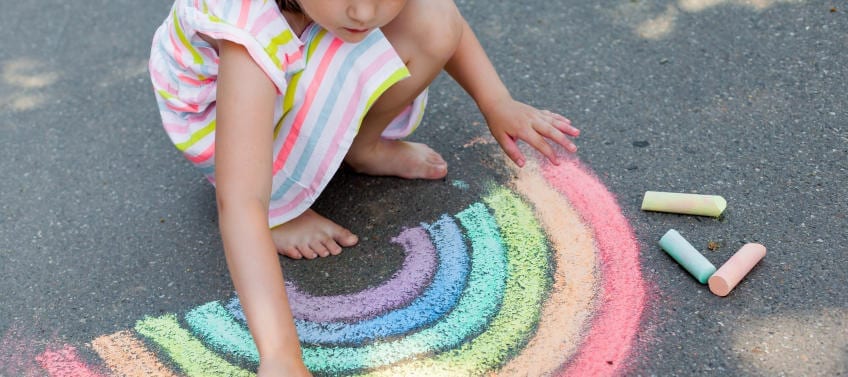 child drawing chalk rainbow