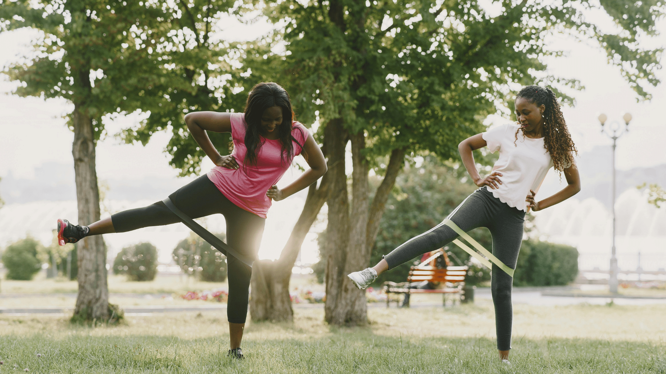 Two women in a park doing leg exercises